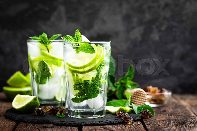 Refreshing mint cocktail mojito with rum and lime, cold drink or beverage with ice on black background, stock photo