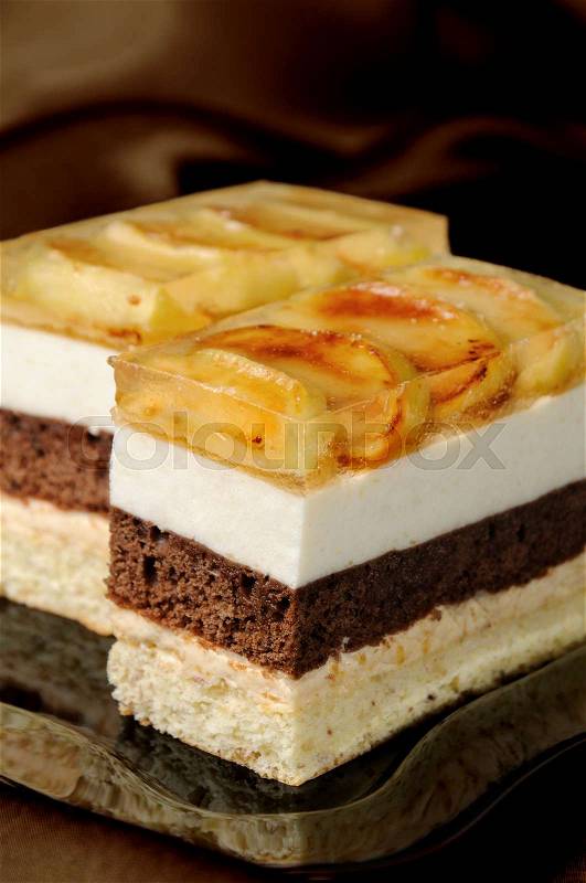 Cake stacked from caramel, apple mousse, chocolate and almond biscuit with a jelly layer of slices caramelized apple, stock photo