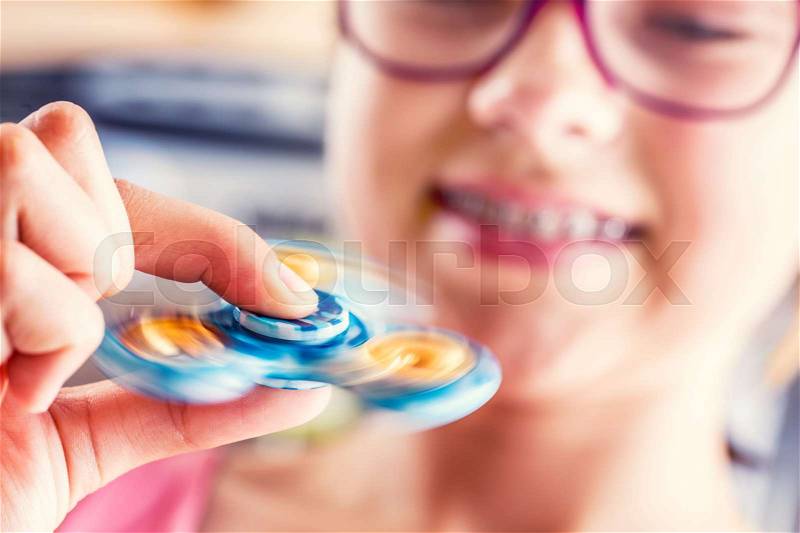 Fidget Spinner. Cute young girl playing with fidget spinner, stock photo