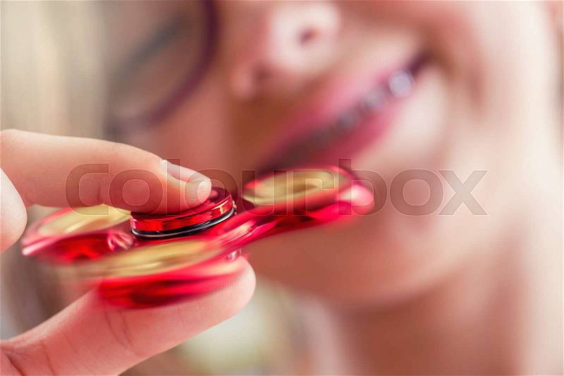 Fidget Spinner. Cute young girl playing with fidget spinner, stock photo