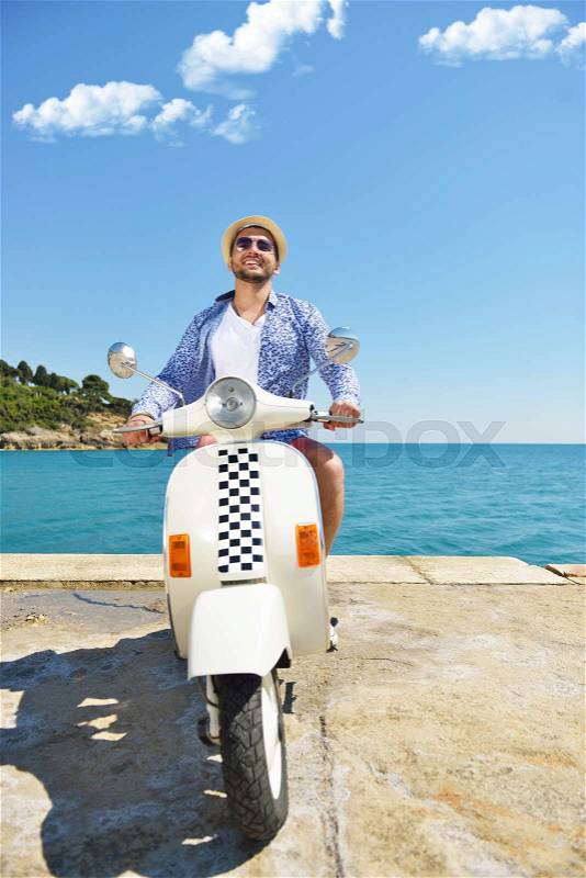 Handsome man posing on a scooter in a vacation context. Street fashion and style, stock photo