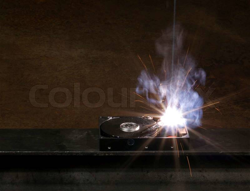 Welding scenery with hard disk drive, welding mask detail and flying sparks, stock photo