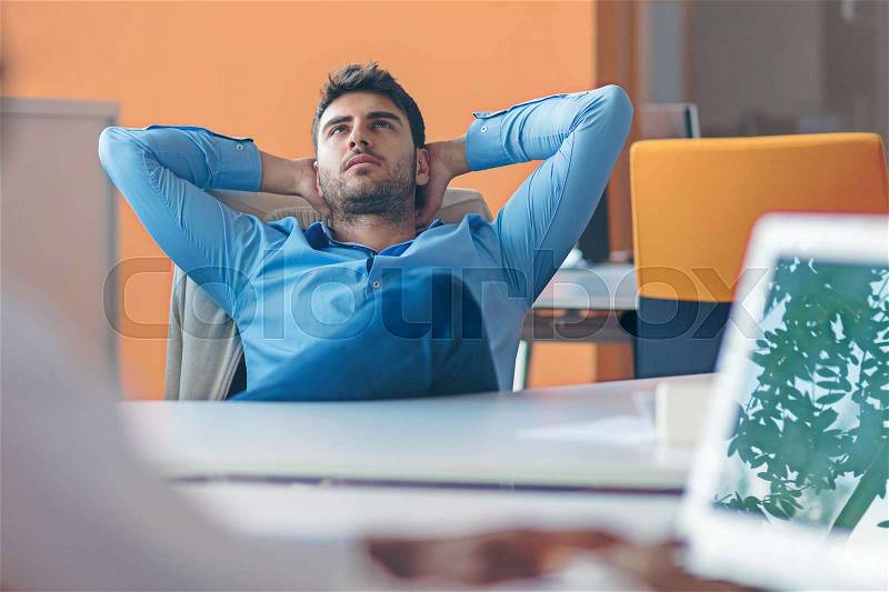 Caucasian business person sitting in office thinking daydreaming hands behind head, stock photo