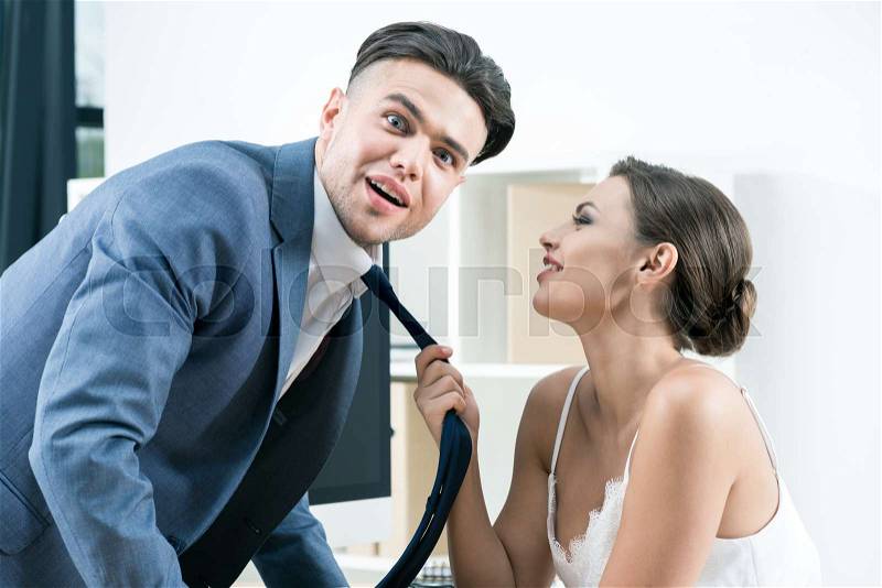 Young sensual businesswoman seducing her amazed boss at office, stock photo