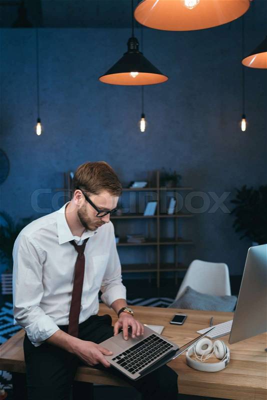 Young businessman in formal wear working on laptop at modern office, stock photo