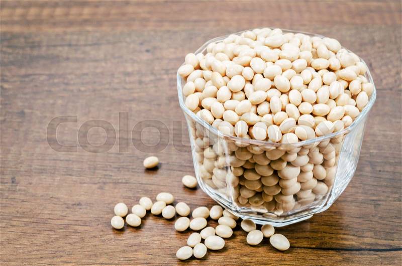 Heap of White Beans in glass cup on wooden background, stock photo