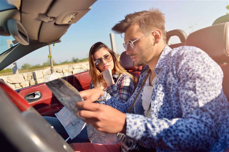 Young loving couple planning their romantic adventure. Joyful young couple smiling while riding in their convertible, stock photo