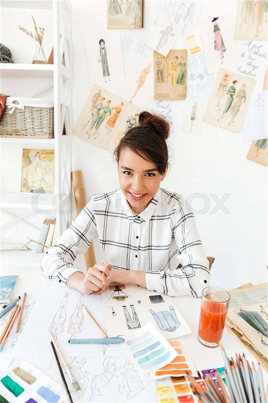 Portrait of a smiling female fashion designer creating sketches at studio, stock photo