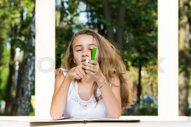 Girl draws on the album in the summer park, stock photo