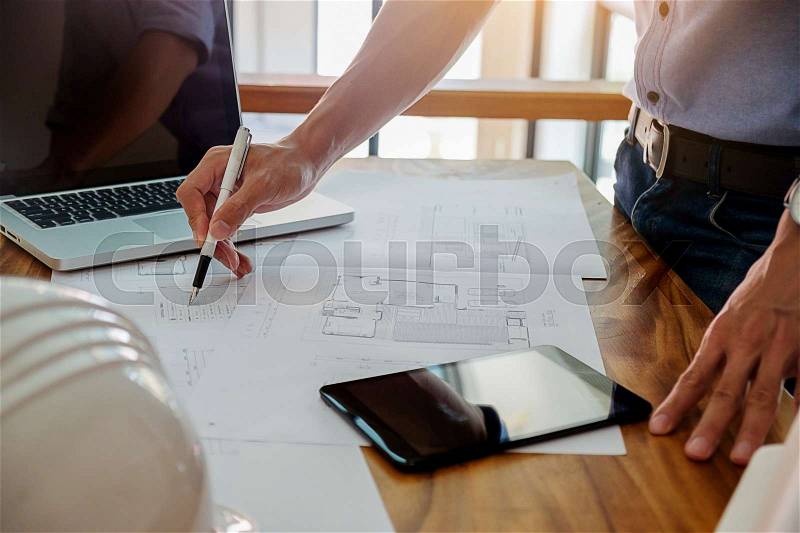 Architects engineer discussing at the table with blueprint - Closeup on hands and project print. , stock photo