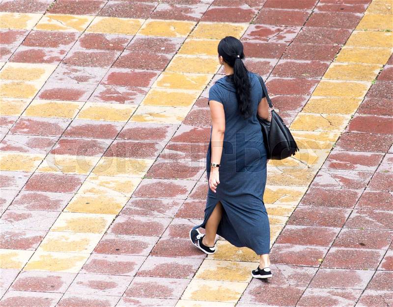 The girl is walking along paving stones , stock photo