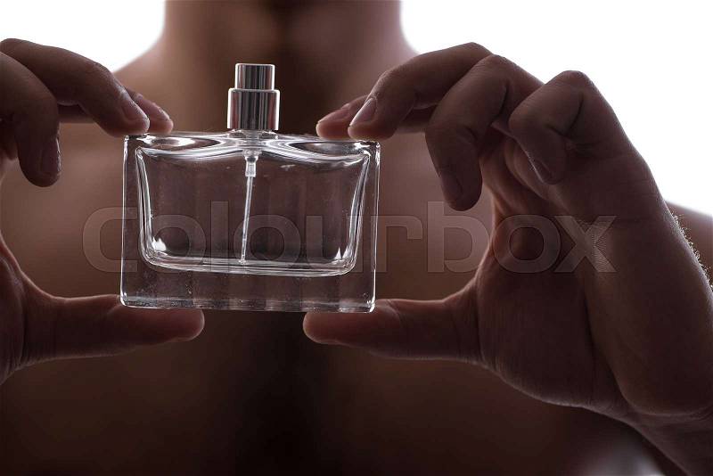 Sexy man with bottle of perfume in low key photo, stock photo