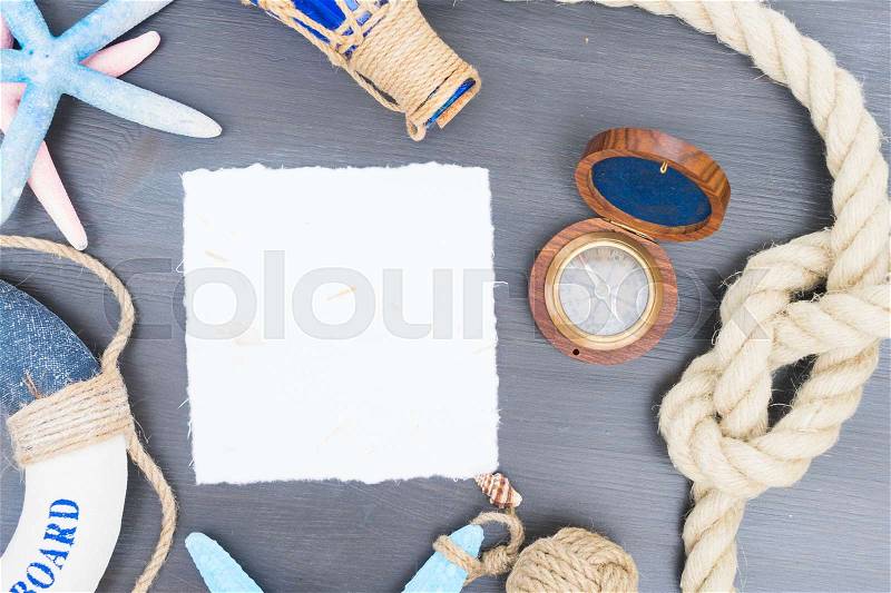 Old vintage compass with marine knot, life-ring and seastars with copy space on white paper note, stock photo