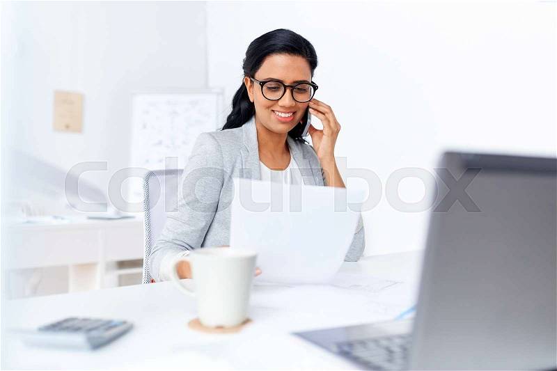 Business, technology, communication and people concept - happy businesswoman with papers calling on smartphone at office, stock photo