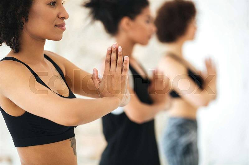 Close up of multicultural group of women practicing yoga in a gym, stock photo