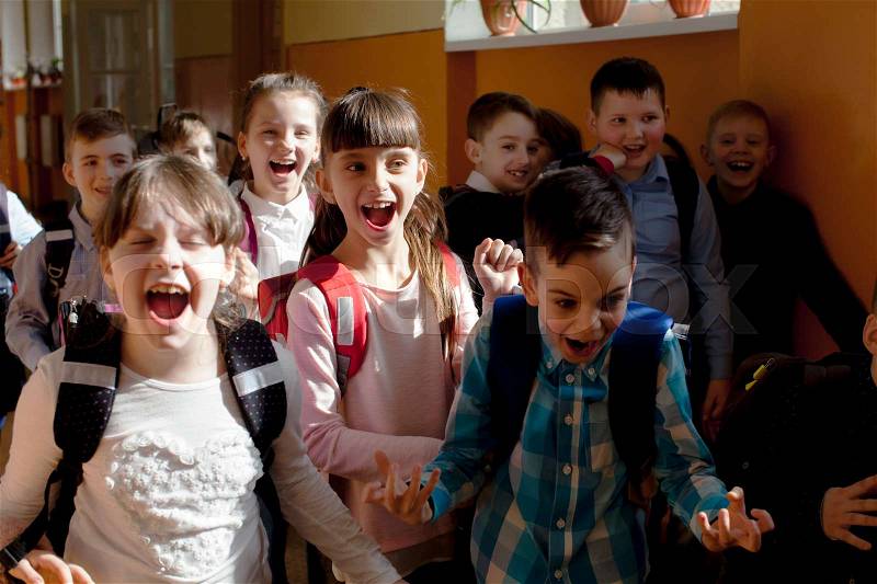 Happy pupils running out of the classroom on summer vacation, stock photo