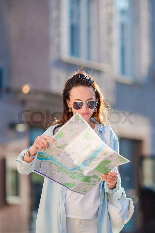 Happy young woman with a city map in Europe. Travel tourist woman with map in Prague outdoors during holidays in Europe, stock photo