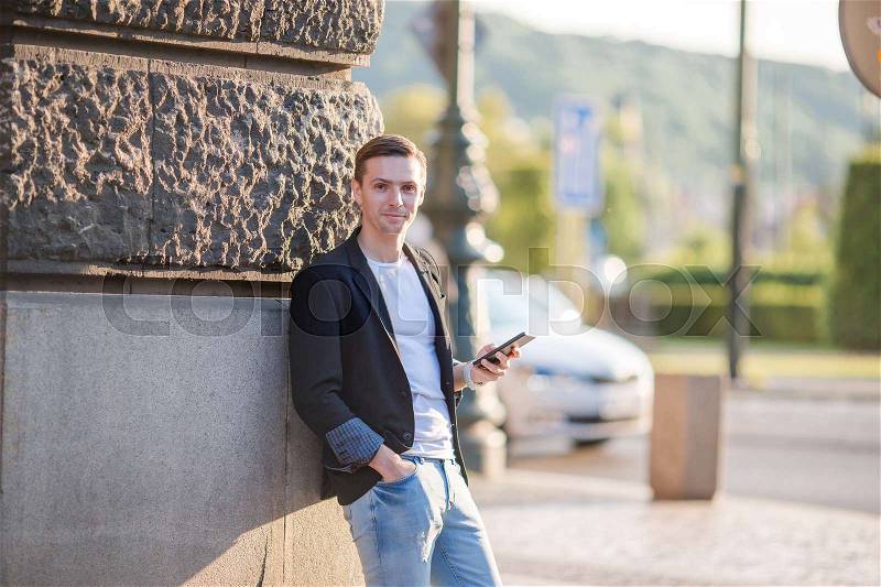 Tourist guy with phone walking along the deserted streets of Europe. Young urban boy on vacation exploring european city, stock photo