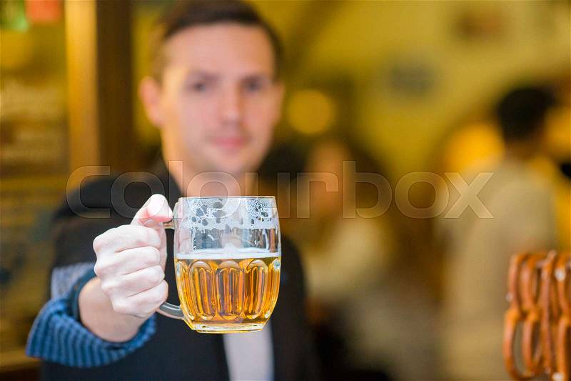 Young man with beer and salted soft pretzels in beer sport bar, stock photo