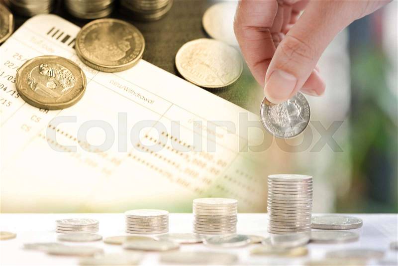 Woman hand putting coin to growing coins stacks duplicate layer with coin on book bank account - Concept of saving money, stock photo