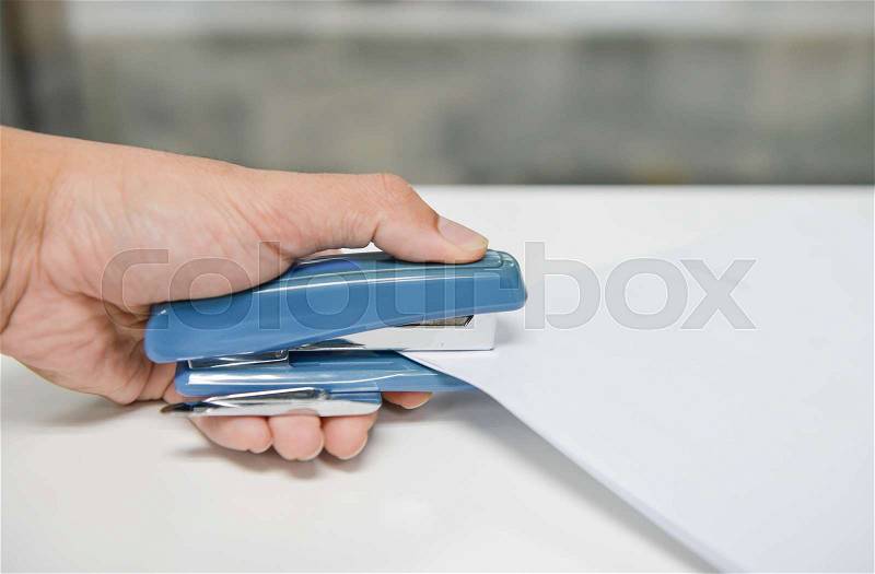 Human hand is Stapling the paper with stapler, stock photo