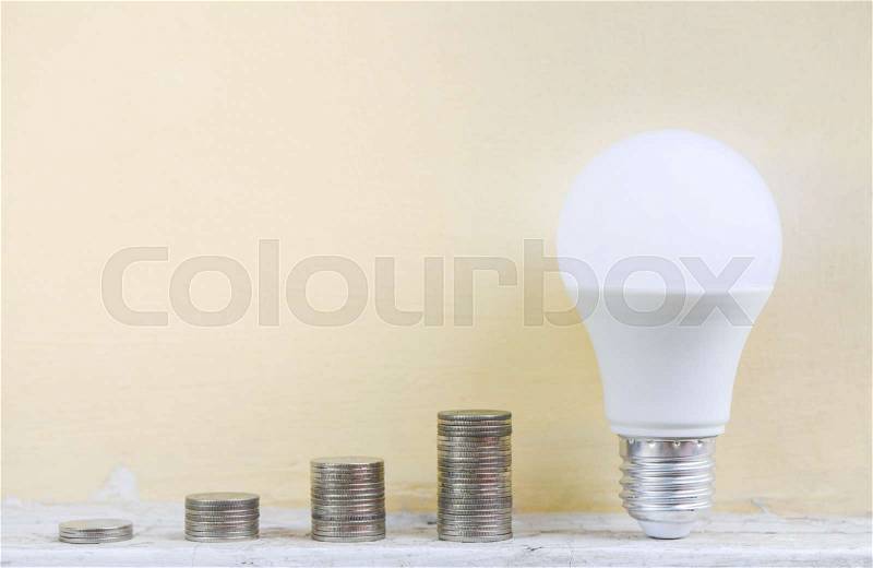 LED bulb on coins stracks for saving energy concept, stock photo