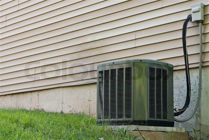 A residential central air conditioning unit sitting outside a home used for regulating the homes AC to a comfortable level, stock photo