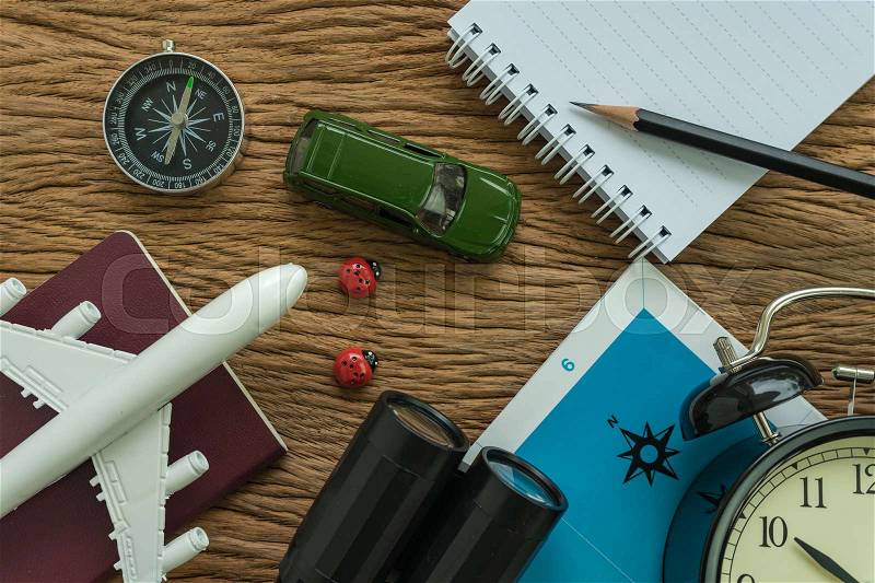Travel planning concept with airplane, passport, compass, binoculars, pencil and paper note on wood table, stock photo