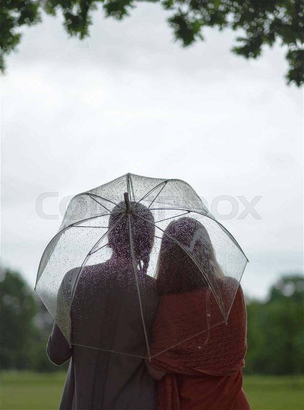 Two women walking park in rain and talk. Friendship and people communication. Rainy day in summer, stock photo