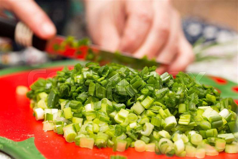 Cook cuts green onions with a knife , stock photo