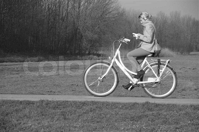 The girl is biking in the park and always online in autumn in black and white, stock photo
