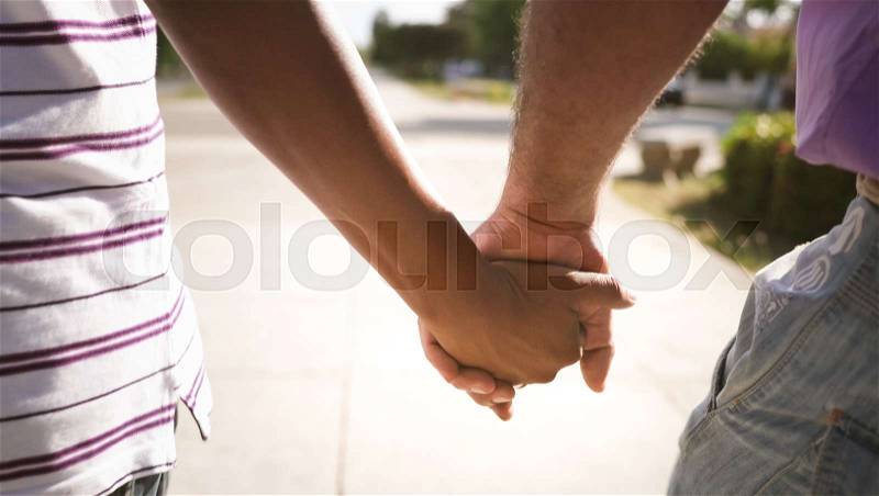 Homosexual couple holding hands and walking on urban street. Gay people, lgbt relationship, with male partners sharing time together, stock photo