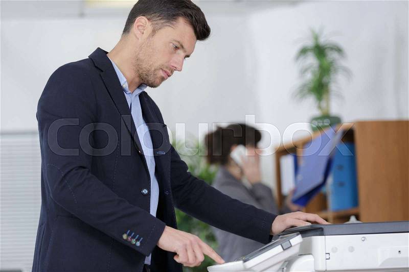 Businessman copy documents on copy machine, stock photo