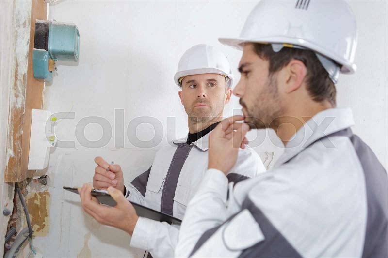 Professional electrician installing components in electrical shield, stock photo