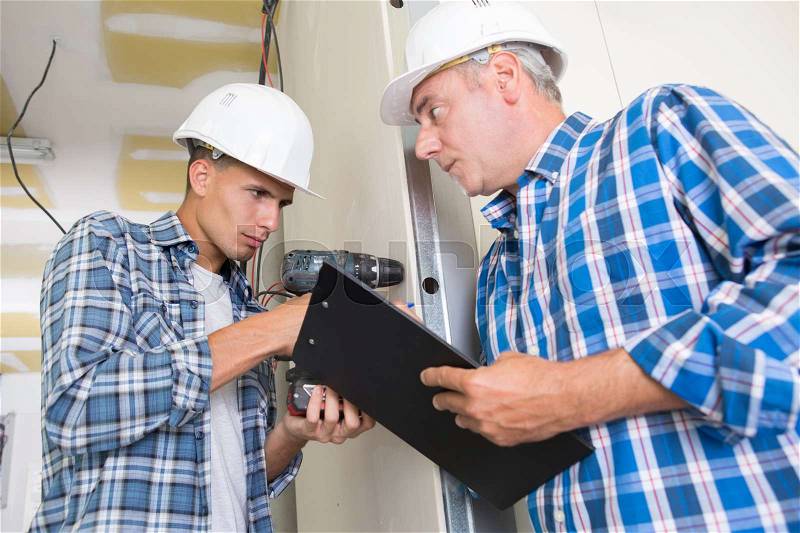 Two electrical workers during apprenticeship, stock photo