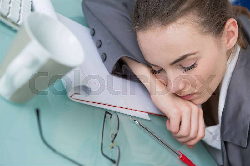 Lazy business woman sleeping on desk in office, stock photo