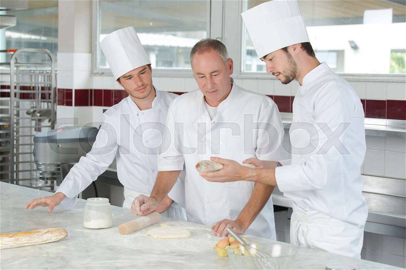 Pastry chef watching students preparing delicious pastries, stock photo