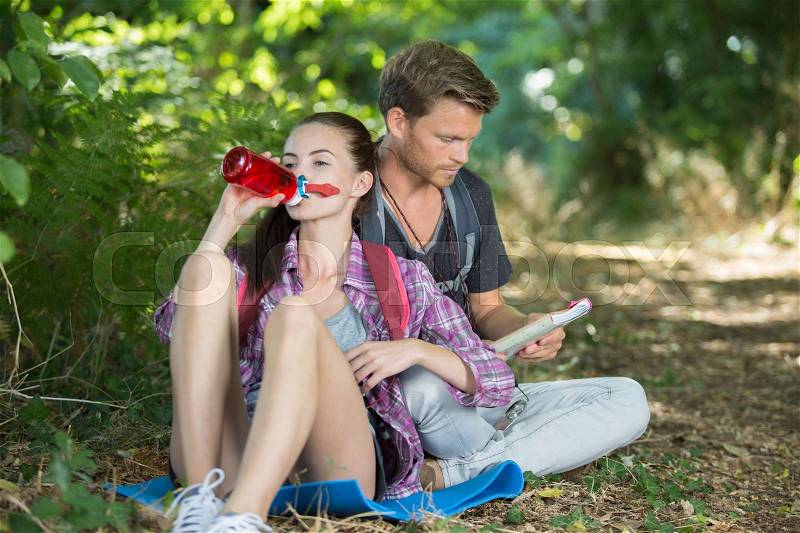 Man and woman drinking water while out hiking, stock photo