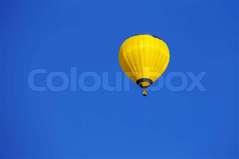 Yellow balloon in blue sky, stock photo