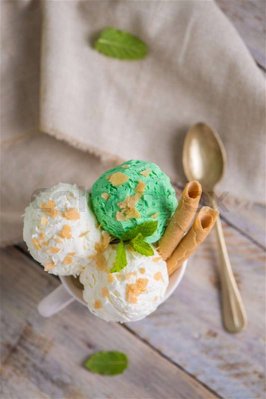 Vanilla and mint ice cream in cup on wooden vintage style background, stock photo