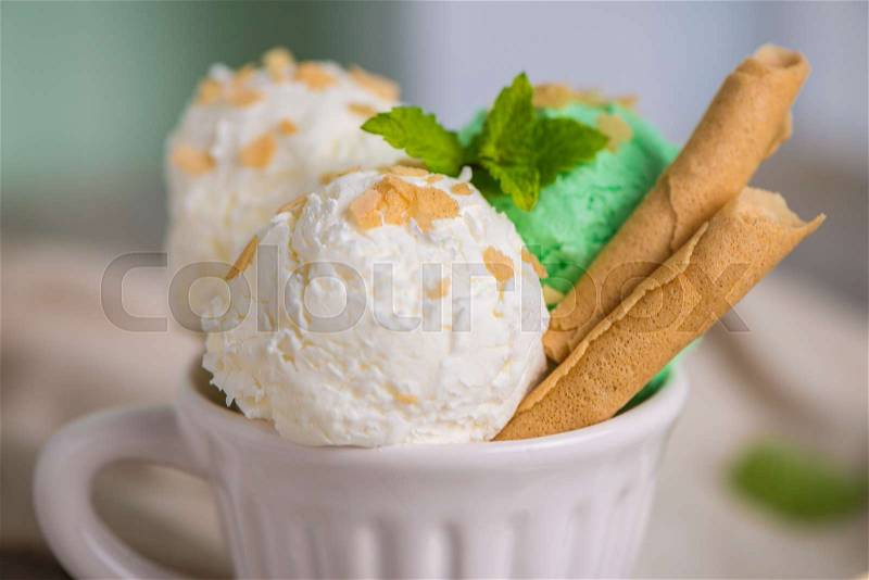 Vanilla and mint ice cream in cup on wooden vintage style background, stock photo