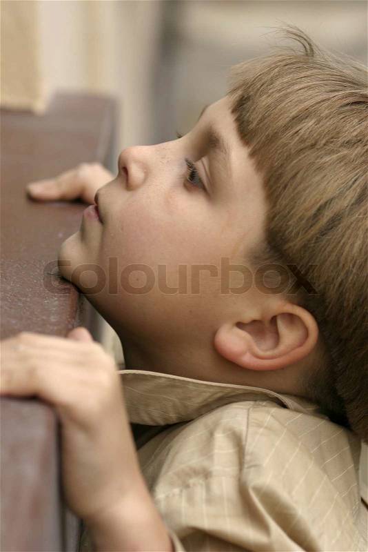 A boy reaching up to a window sill, stock photo