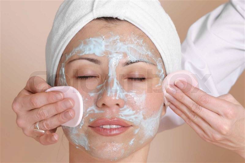 Beautician cleansing the skin of a female customer, stock photo