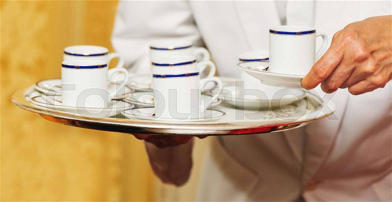 Waiter carrying tray with coffee cups on some festive event, party or wedding reception, stock photo