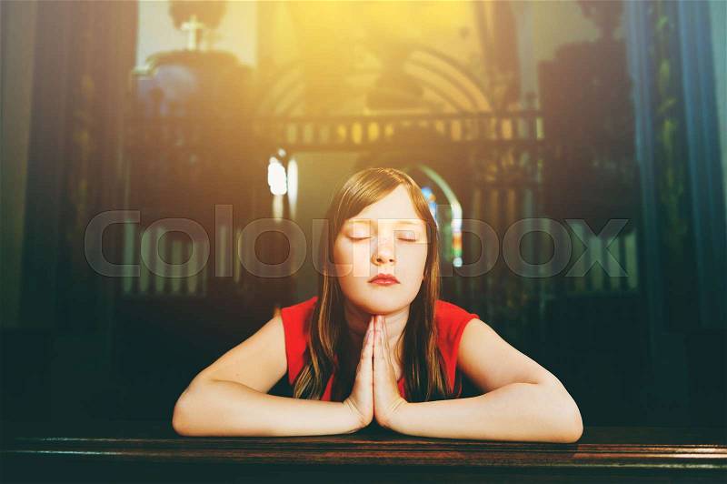 Child praying in church, stock photo