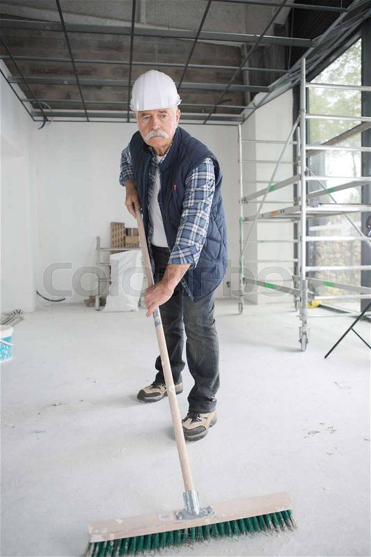 Male worker cleaning warehouse with mop, stock photo