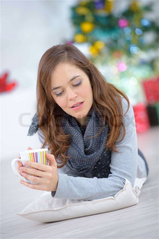 Woman laying on the floor with a cup of coffee, stock photo