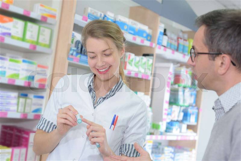 Pharmacist showing label to customer, stock photo