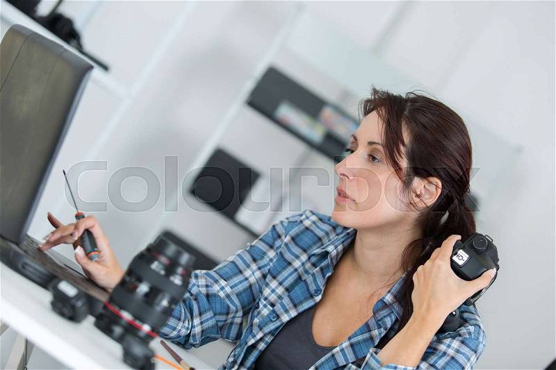 Photographer checking his digital pictures on laptop in agency, stock photo