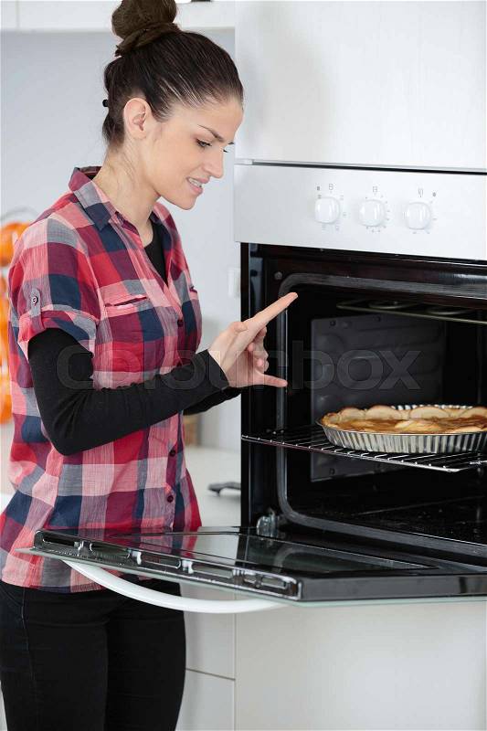 Woman placing a cake in the oven, stock photo